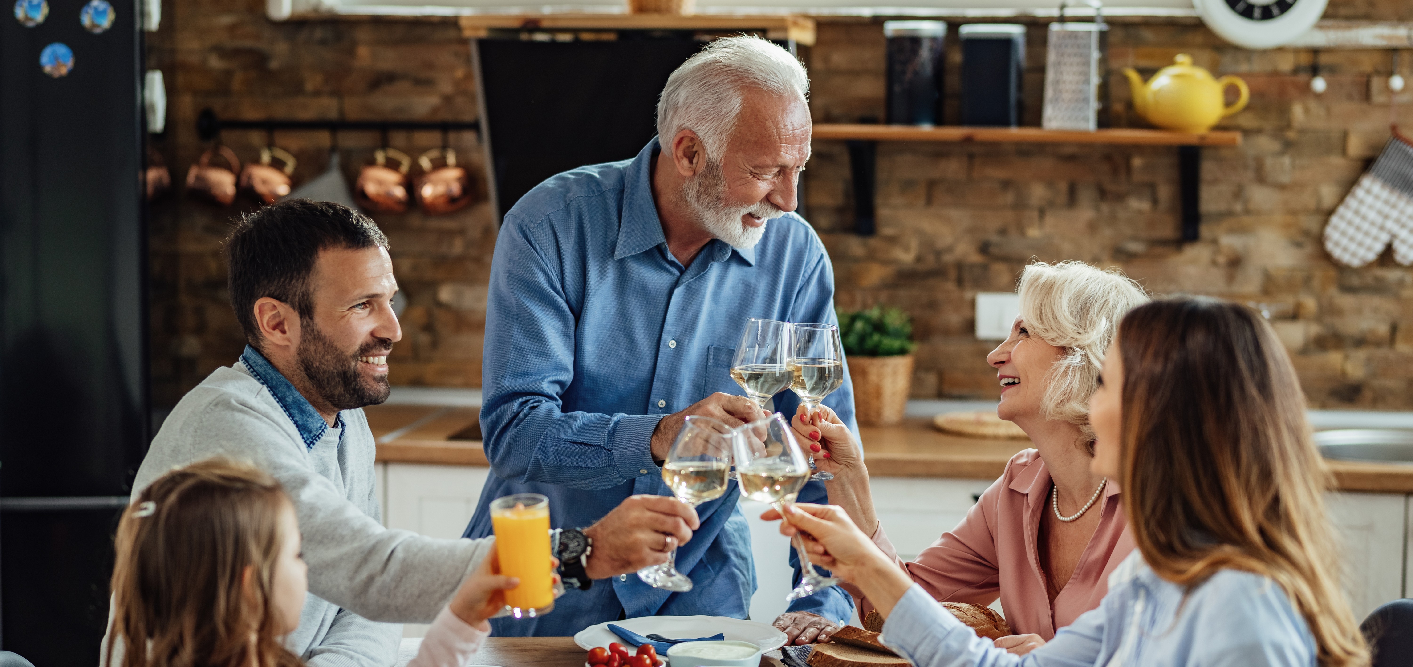 happy-extended-family-enjoying-lunch-toasting-dining-table-focus-is-senior-couple.jpg