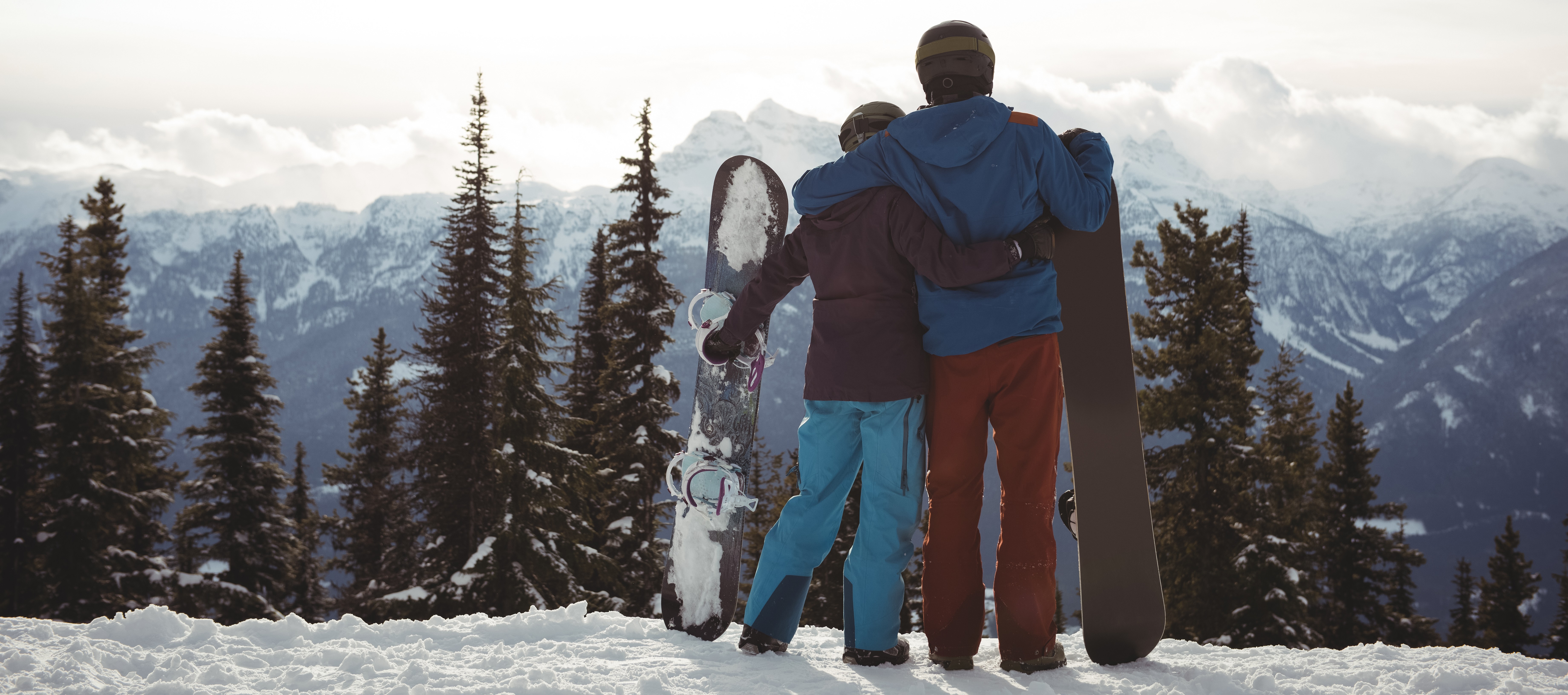 rear-view-couple-holding-snowboard-mountain-winter-against-sky.jpg